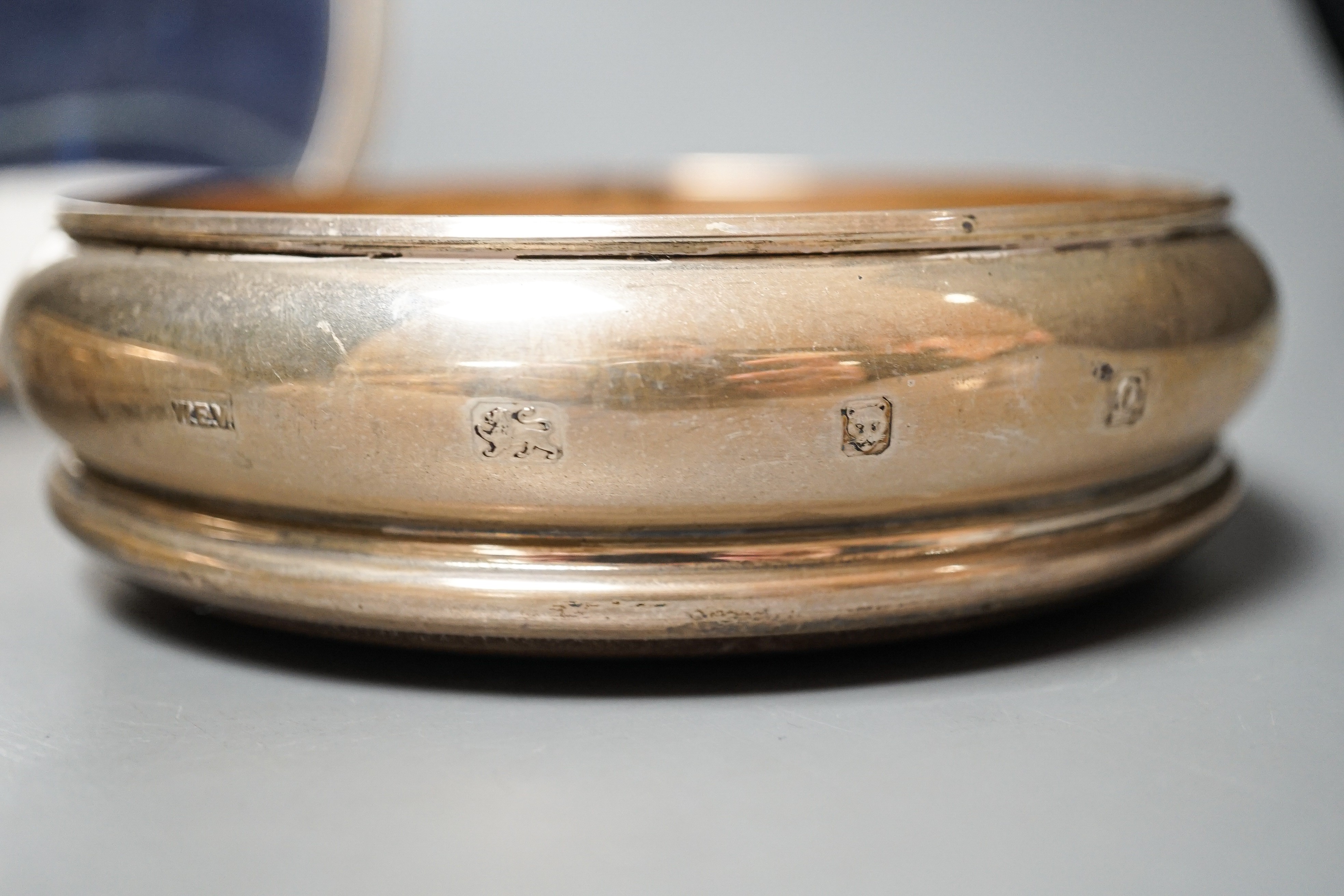 A pair of modern silver mounted wine coasters, W.E.V. London, 1990, (a.f.), 12.2cm and a 925 mounted oval photograph frame.
